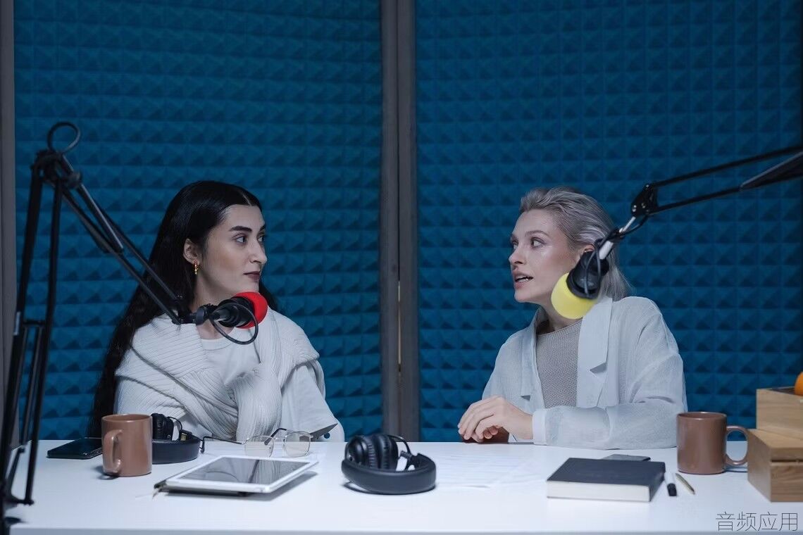 two-women-having-a-conversation-while-sitted-behind-a-crowded-table-in-a-studio.avif.jpg