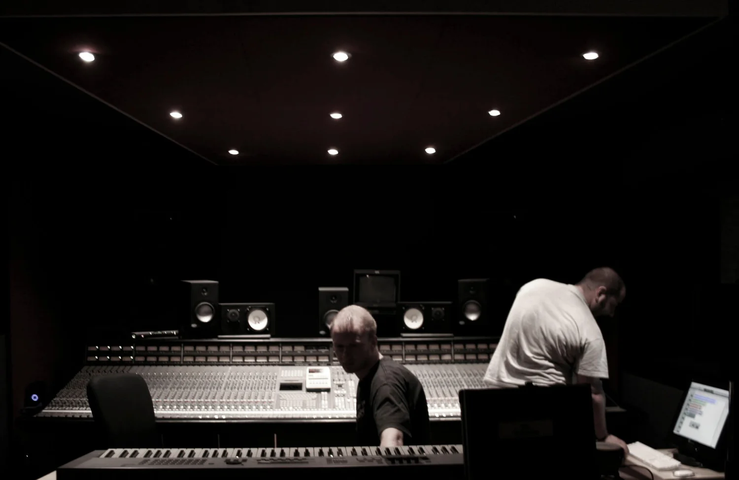 A darkly lit recording studio with a large analog console.webp.png